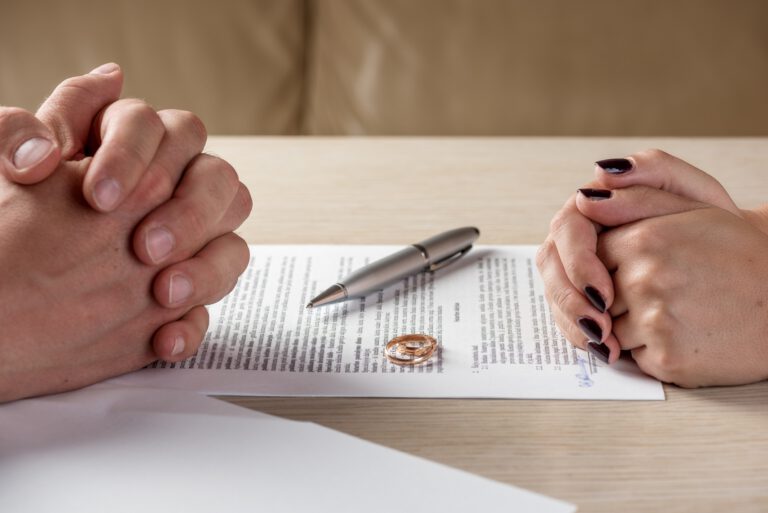 Hands of wife and husband signing divorce documents or premarital agreement